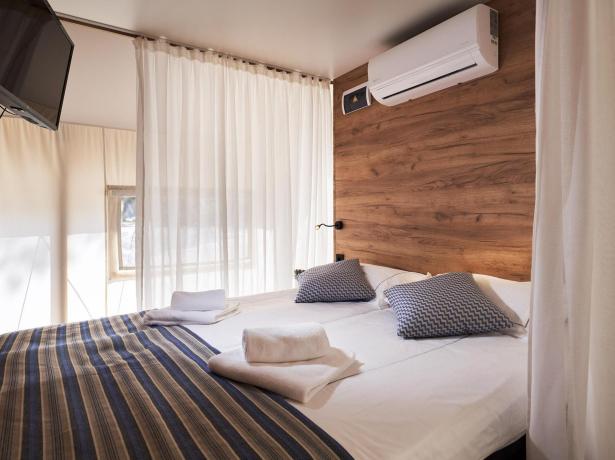 Chambre moderne avec lit double, TV et climatisation.