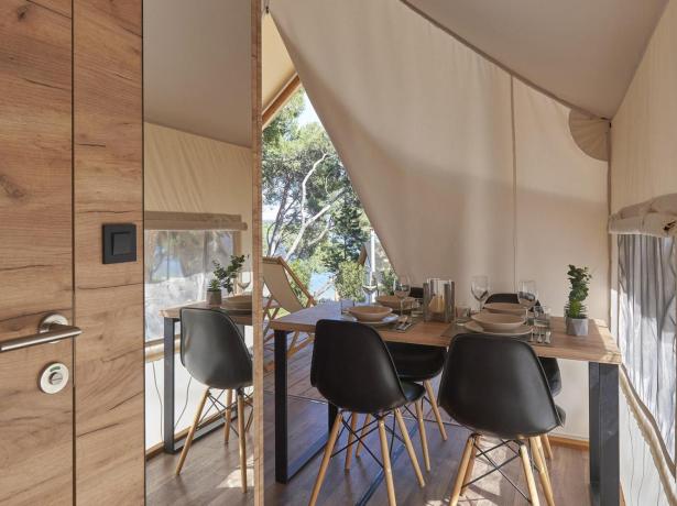 Interieur van een glamping tent met eettafel en moderne stoelen.