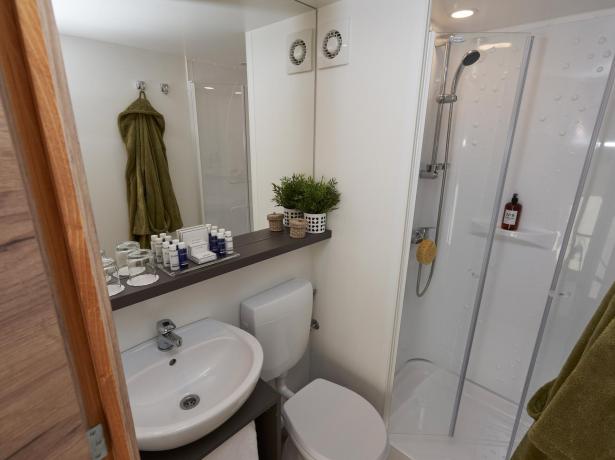 Salle de bain moderne avec douche, lavabo, WC et articles de toilette.